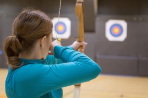 Femme de dos qui vise une cible avec un arc (tir à l'arcà