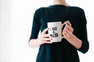 Femme avec une robe noire portant une tasse avec l'inscription 'like a boss'