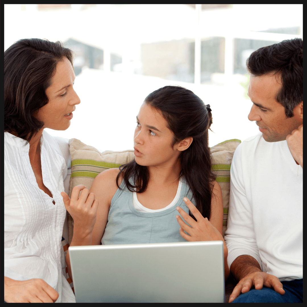 Une adolescente entourée de ses parents. Ils sont assis sur un canapé et consultent ensemble un pc portable.